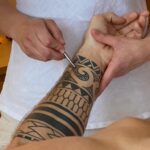 Nadja Stenzl beim Entstören einer Tattoo-Narbe eines Kunden mittels eines Akupressurstiftes.